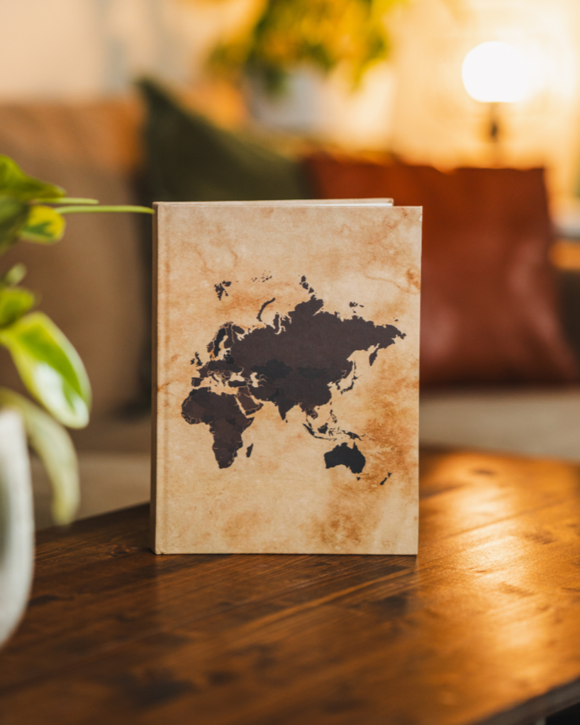 Notebook with world map design on a wooden surface in a cozy room.
